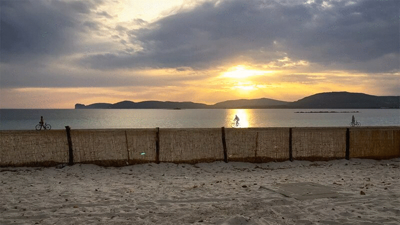 撒丁岛阿尔盖罗日落海滩上的自行车手图片下载