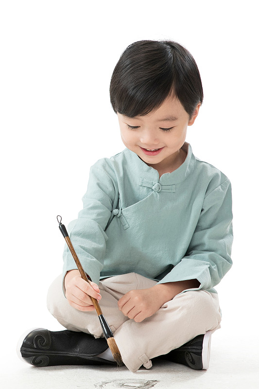 可爱的小男孩坐在地上用毛笔写字图片素材