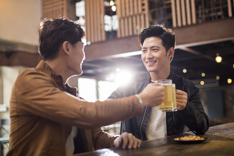 快乐的年轻男士在酒吧喝酒干杯图片素材