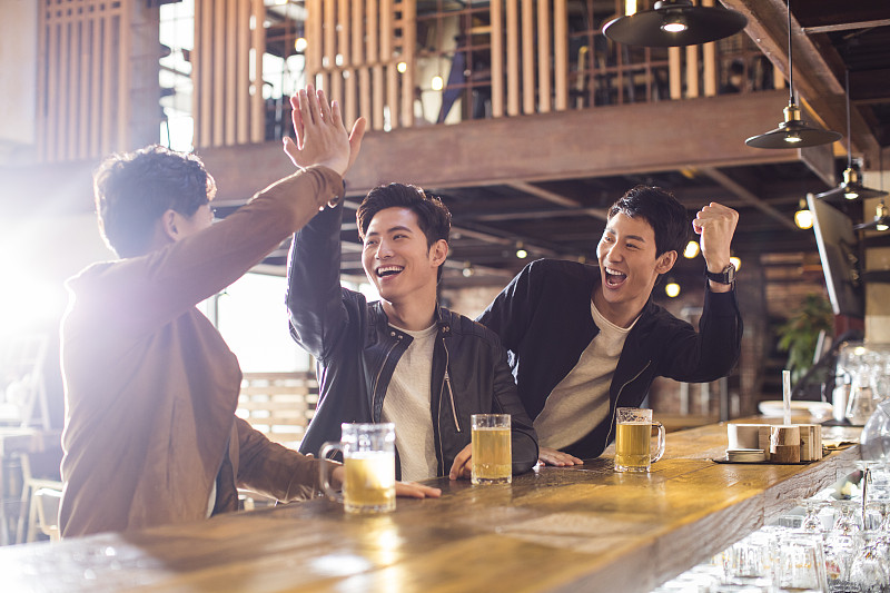 快乐的年轻男士在酒吧喝酒欢呼图片下载