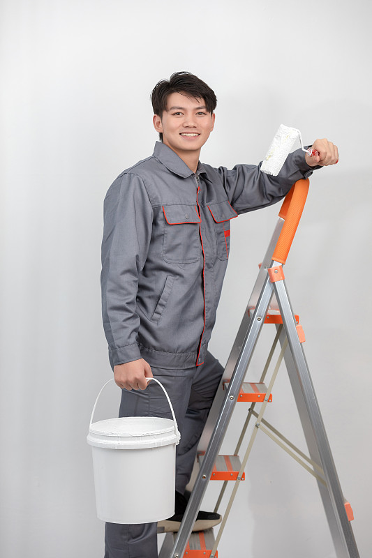 白色背景里穿着工作服攀爬梯子的亚洲年轻男子图片下载