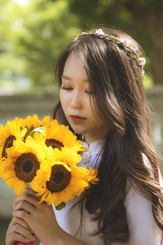 越南河内，一名手持向日葵的年轻女子的肖像图片素材