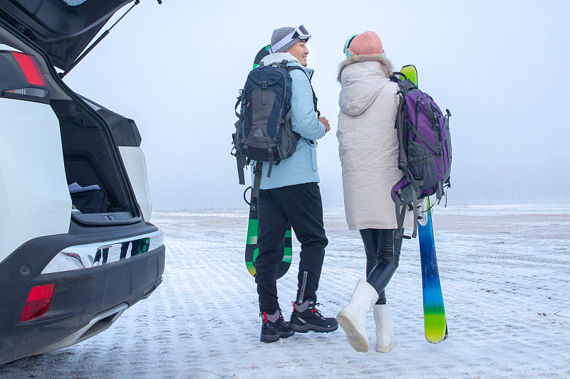 青年伴侣拿着滑雪板的背影图片下载