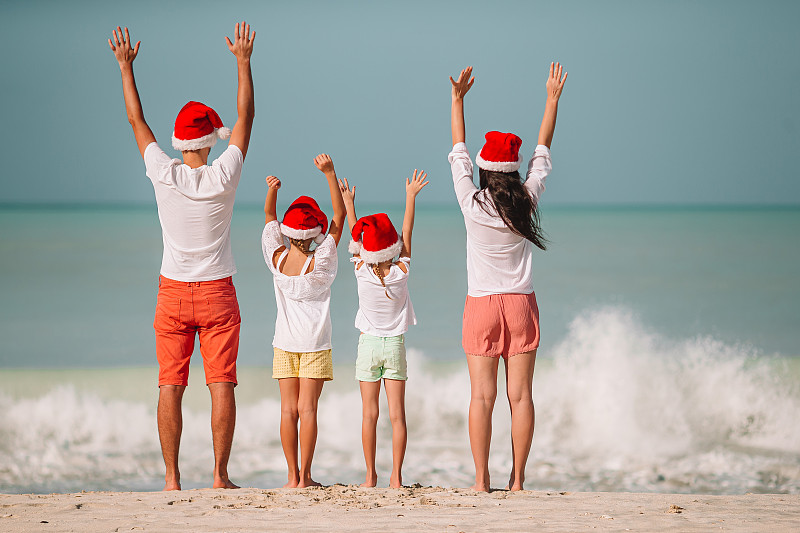 戴着圣诞老人帽的海滩上的家人图片素材