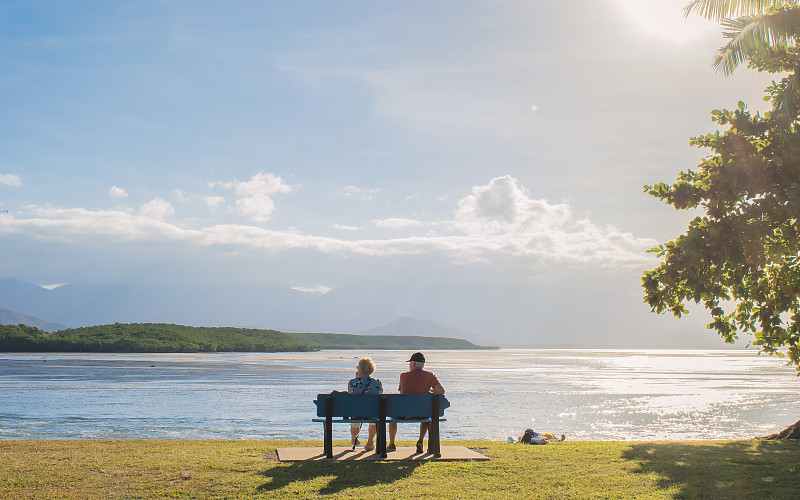 一对幸福老夫妻坐在澳大利亚道格拉斯港海边长椅上图片下载