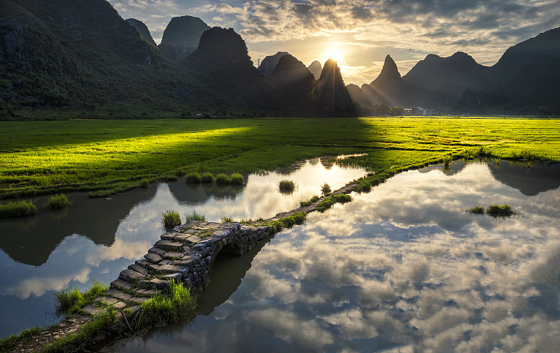 广西壮族自治区桂林市田心村状元桥的清晨，太阳从群山间升起图片素材