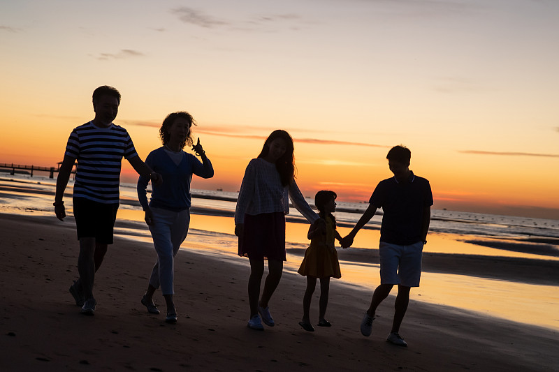 夕阳下在海边散步的幸福家庭图片素材