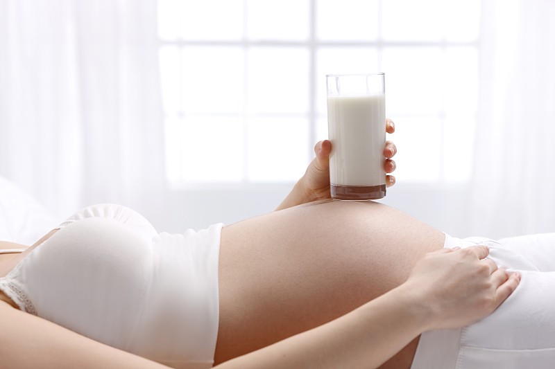 孕妇拿着牛奶放在肚子上图片下载