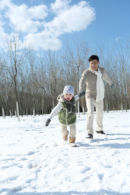 父亲和儿子在雪地上奔跑图片素材