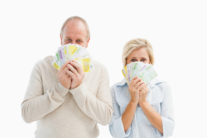 一对幸福成熟的夫妇对着白色背景上的钱微笑图片下载