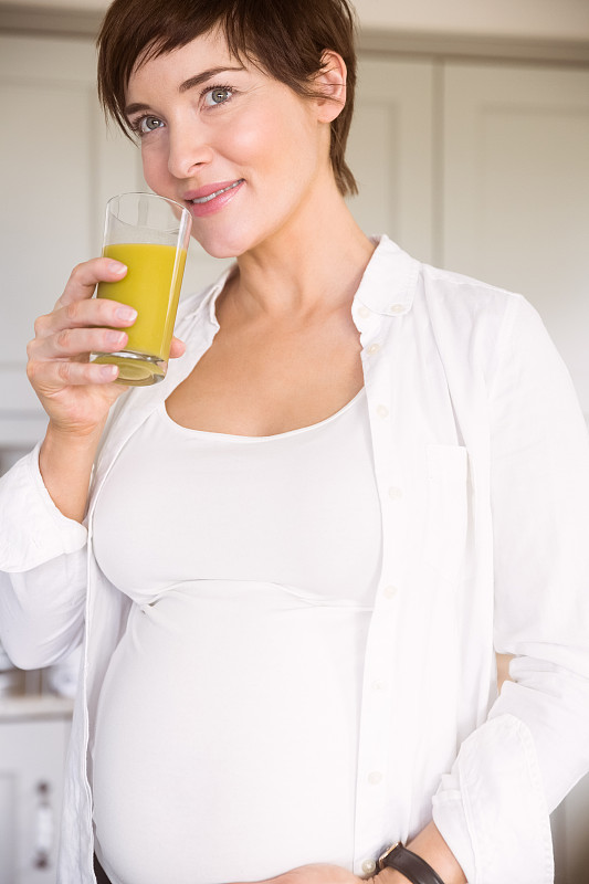 孕妇在家厨房里喝着橙汁图片素材