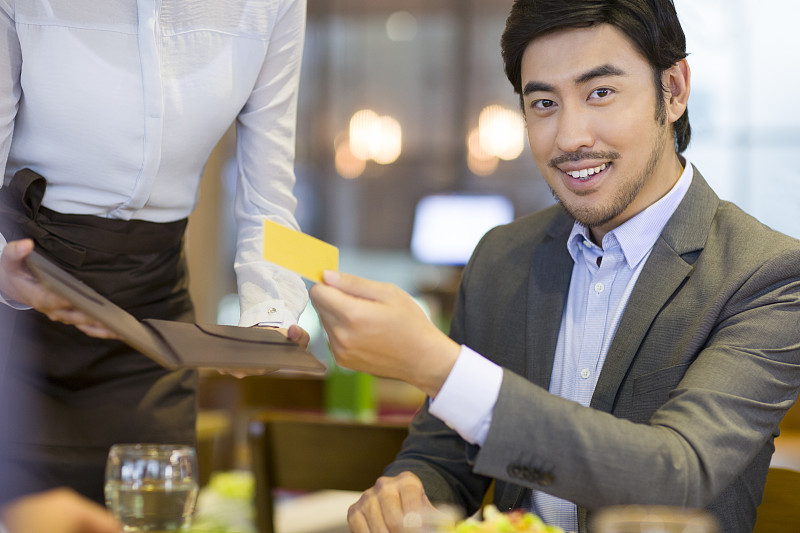 商务男士在餐馆使用信用卡结账图片下载