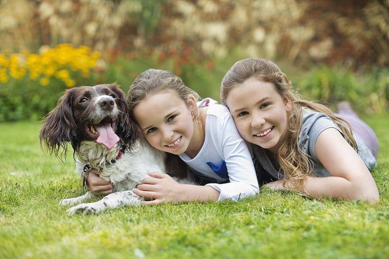 微笑的女孩放松与狗在草坪上图片素材