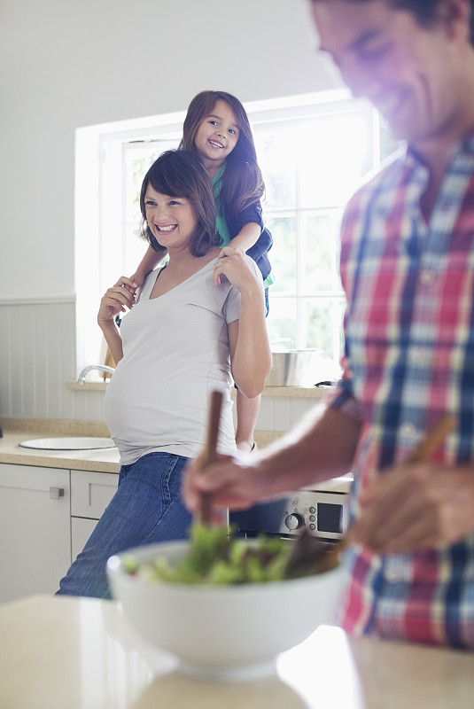 怀孕的母亲和女儿看着父亲扔沙拉图片下载