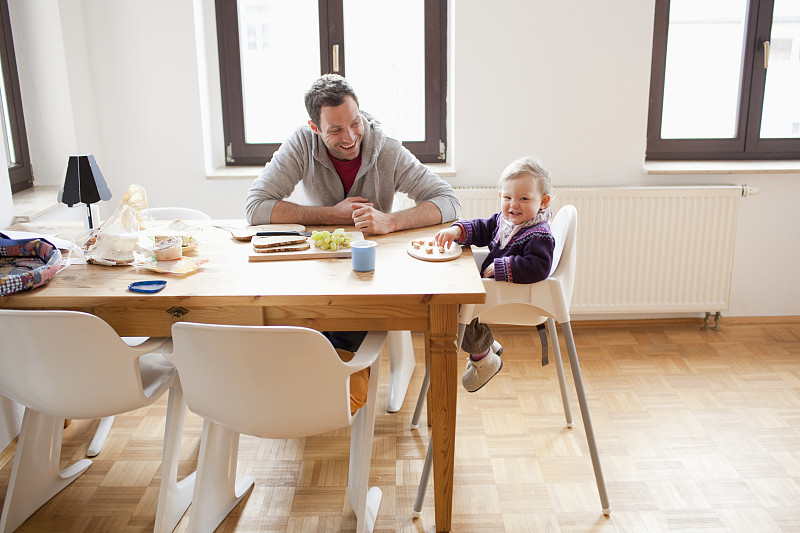 父亲和女儿(6-12个月)坐在餐桌旁图片下载