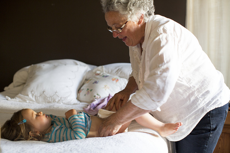 美国加州，老奶奶在床上给孙女换尿布图片下载
