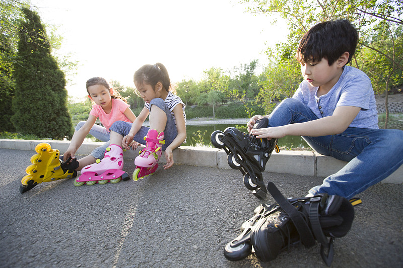 儿童坐在路边穿直排轮鞋图片下载