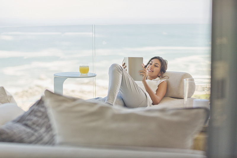 女人放松阅读在豪华阳台上的躺椅与海洋的vie图片下载