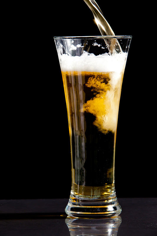在黑色背景下，装满啤酒的玻璃杯图片下载