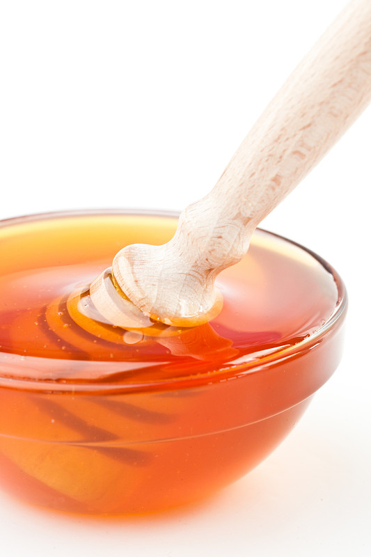 特写的蜂蜜碗与蜂蜜勺对白色的背景图片素材