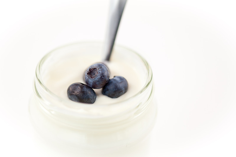 特写的一罐酸奶与蓝莓在白色的背景图片下载