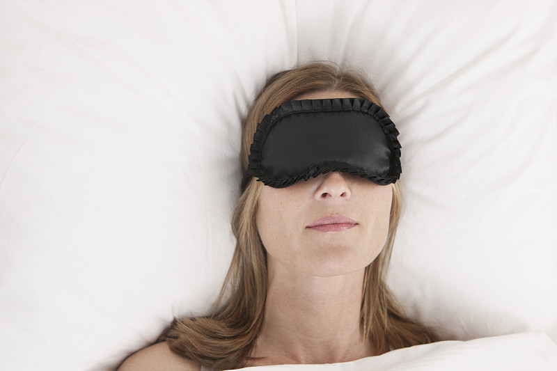 德国，一个戴着眼罩的女人躺在床上图片下载