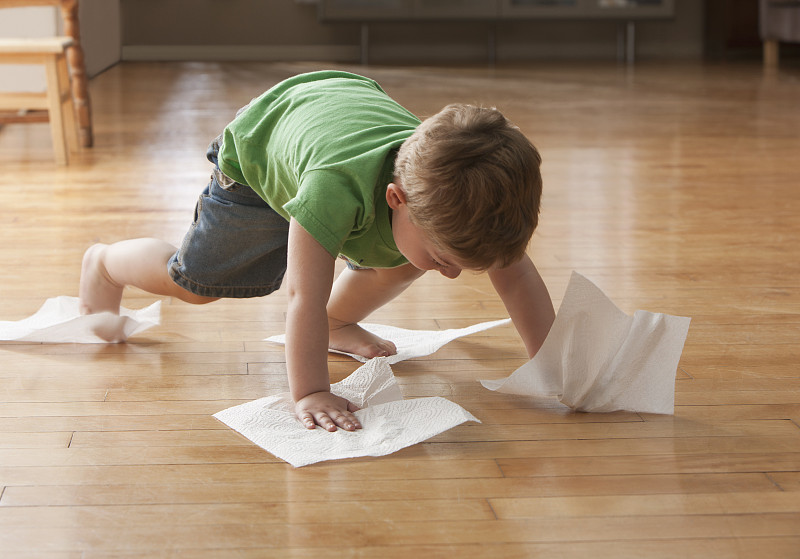 小男孩用纸巾擦地板图片素材