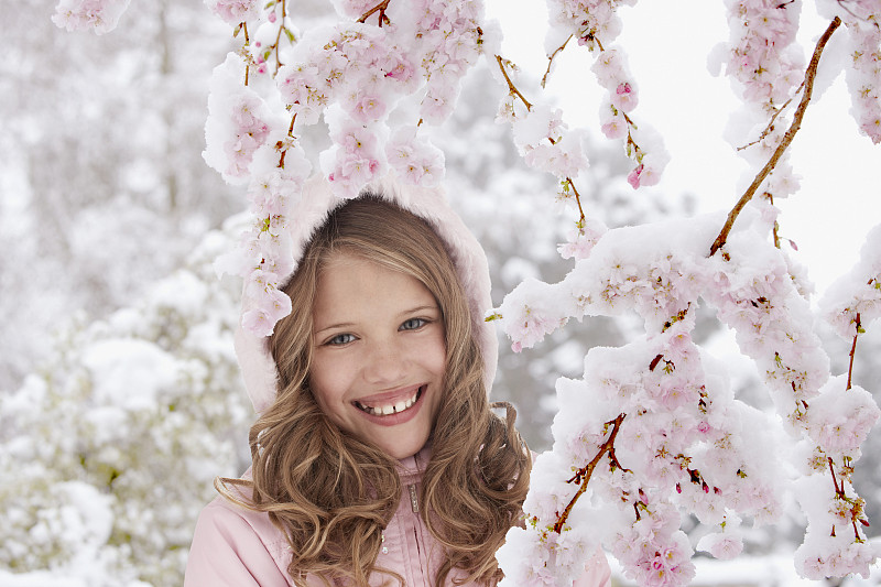 微笑的女孩站在开花的树下图片下载