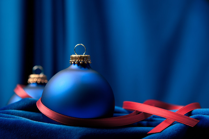 蓝色天鹅绒上的红丝带和圣诞装饰品图片下载