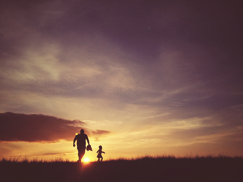 父亲和女儿在日落时分跑上山图片下载