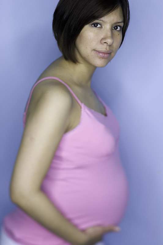 孕妇抱着肚子在摄影棚里拍照图片下载