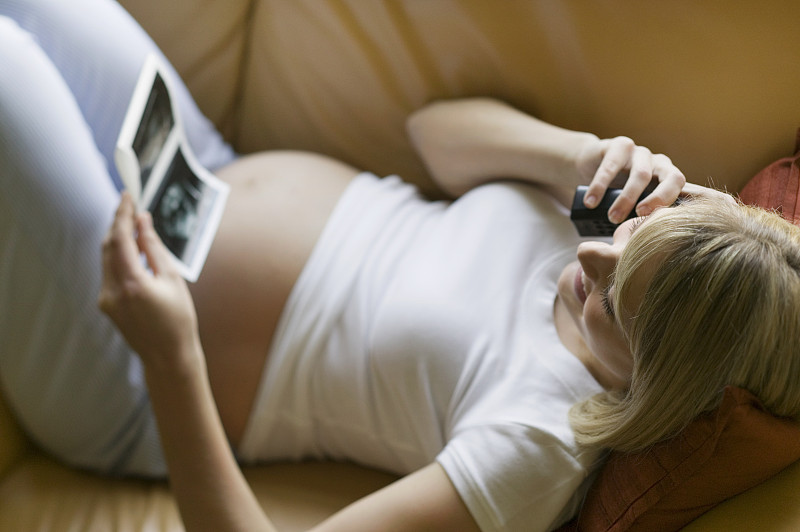 孕妇在客厅的沙发上打电话图片下载
