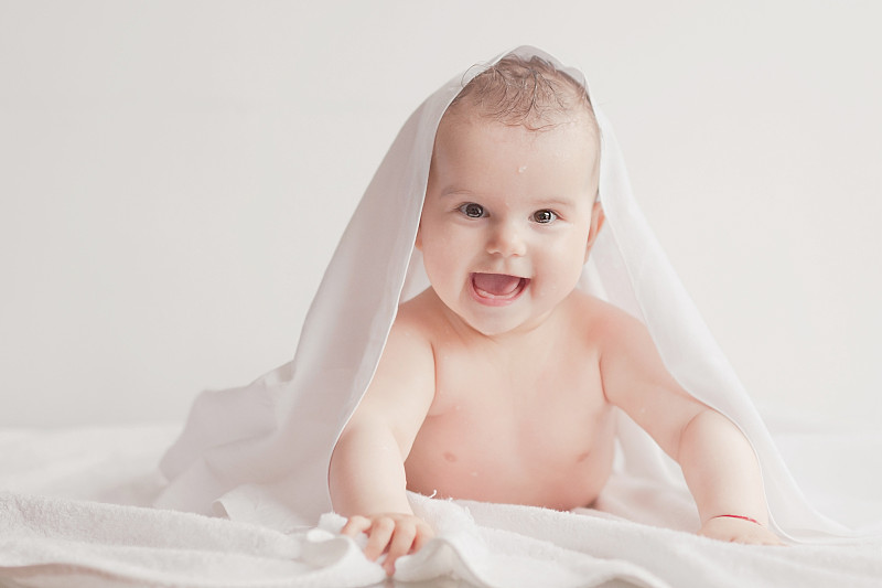 微笑的小婴儿裹在浴巾里图片下载