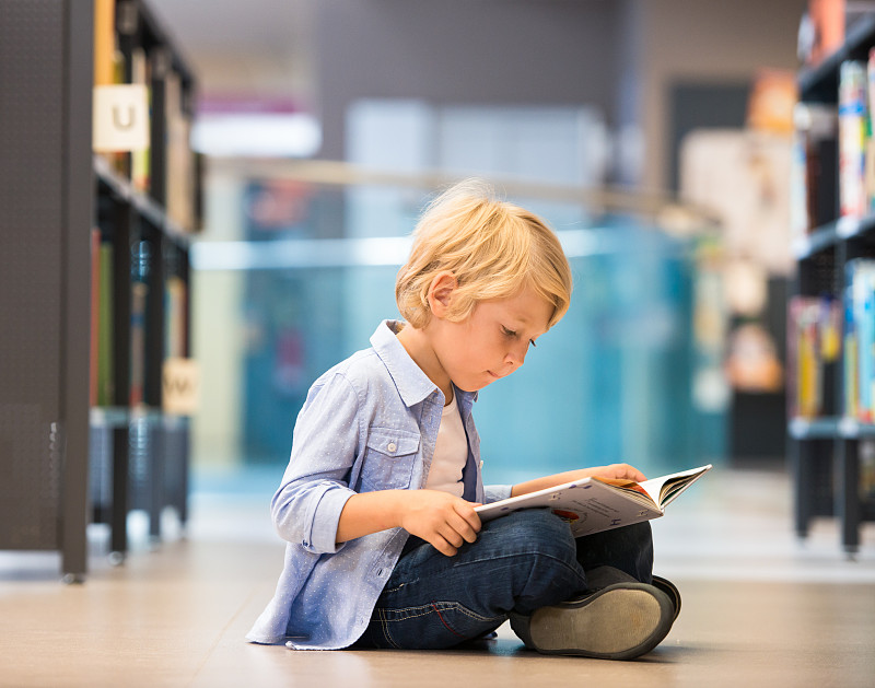 可爱的小男孩坐在图书馆里图片下载
