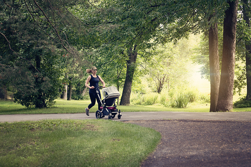新妈妈在公园里推着婴儿车慢跑。图片下载