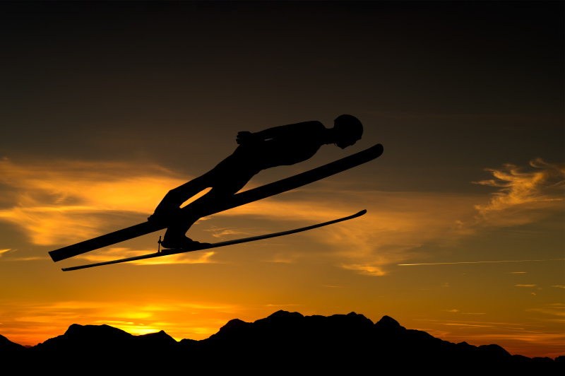 在阳光下的半空中跳台滑雪的侧面视图图片下载