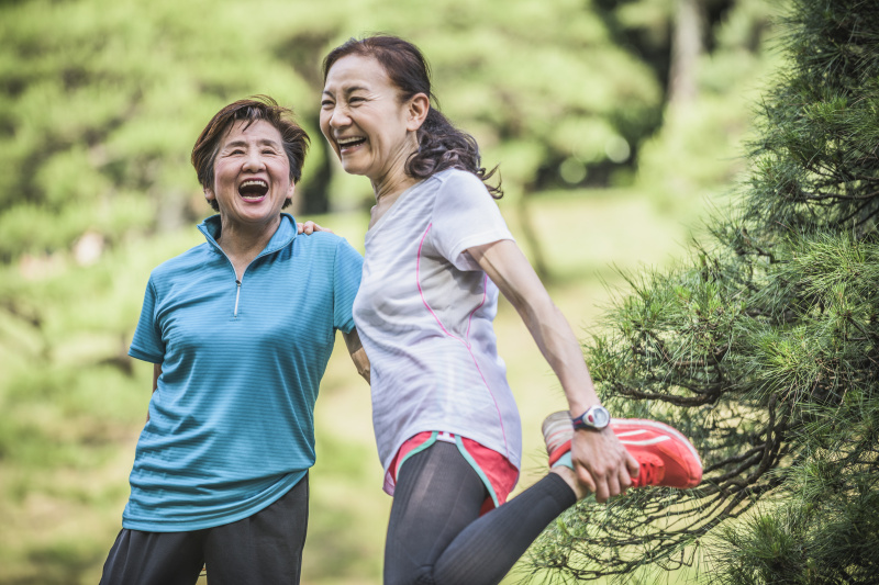 两个活跃的日本妇女笑着，一个伸着腿图片素材