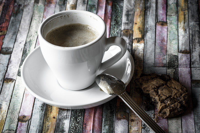 一杯咖啡和彩色木头上的巧克力饼干图片素材
