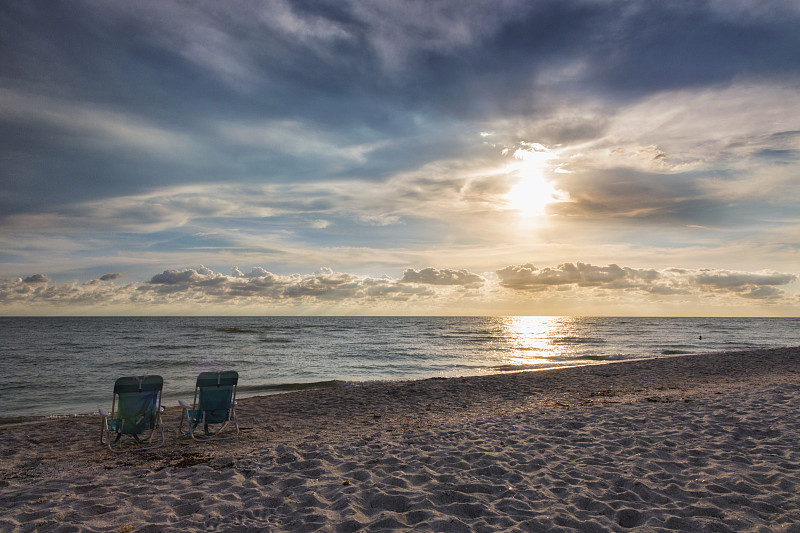 日落时分沙滩上的两把空椅子图片下载
