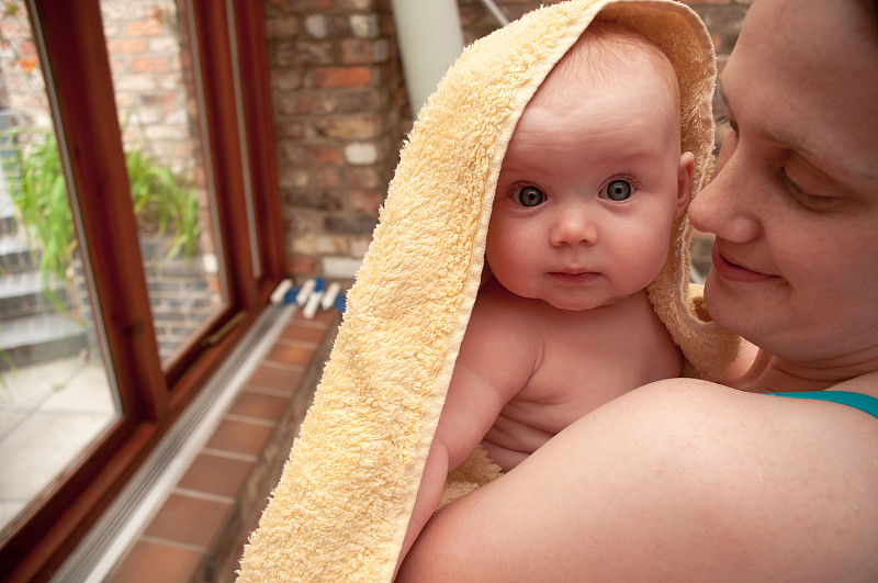 女婴裹着毛巾，由母亲抱着图片下载