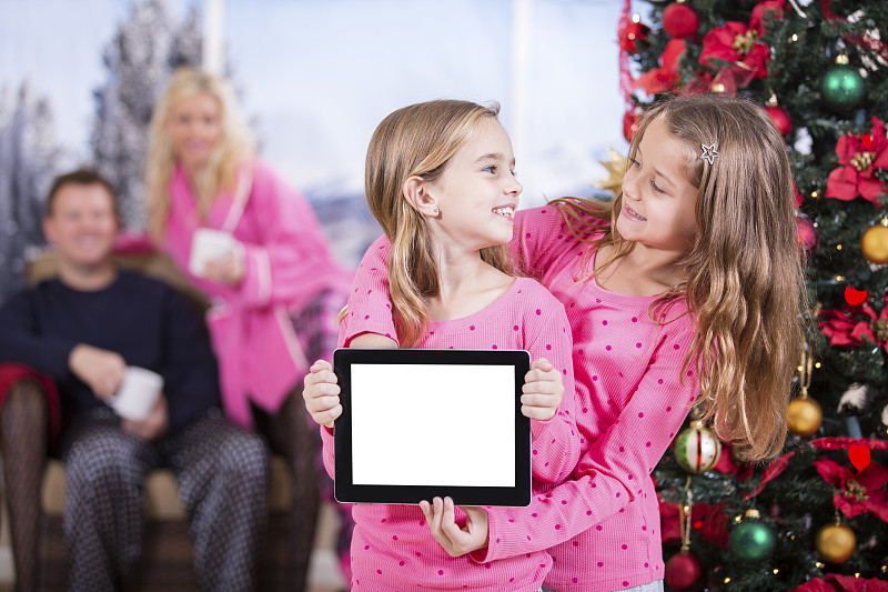 小女孩兴奋地打开数码平板电脑的圣诞礼物。空白屏幕。图片素材