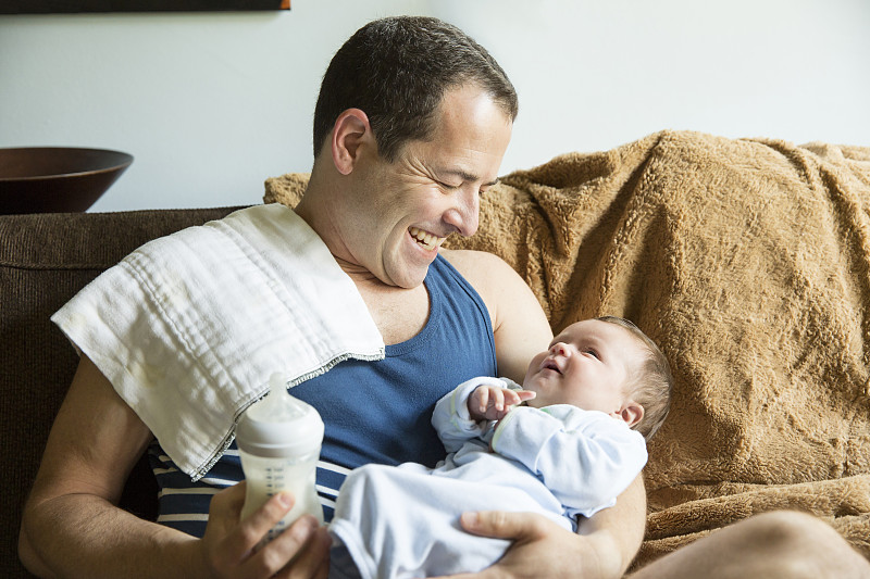 一个白人父亲抱着一个男婴在客厅里图片下载
