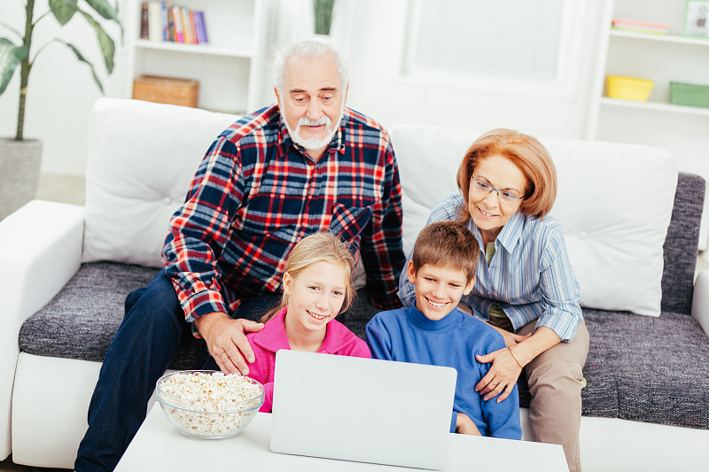 祖父母和孙辈一起看笔记本电脑图片下载
