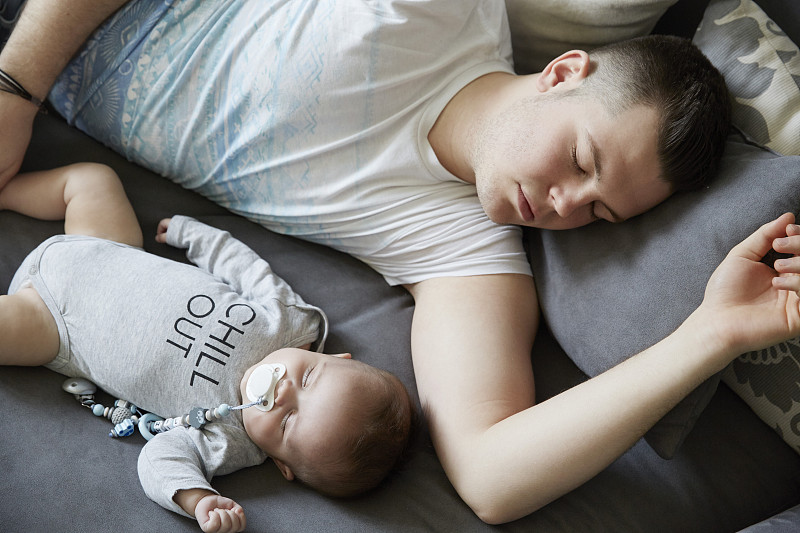 年轻的父亲和婴儿睡在沙发上图片下载