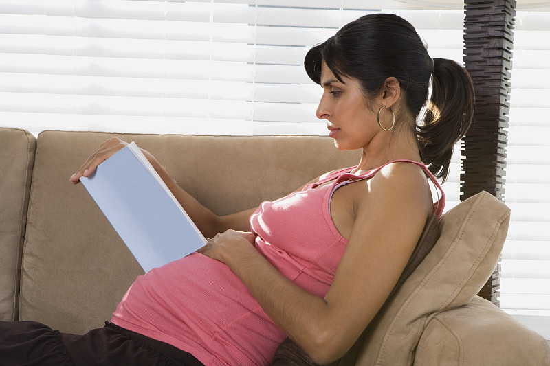 一个正在看书的孕妇的侧面图片下载