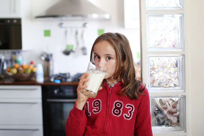 一个10岁的女孩在喝一杯牛奶图片素材