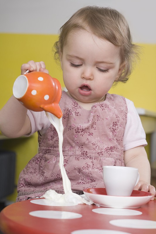 小女孩把牛奶洒在桌子上图片下载