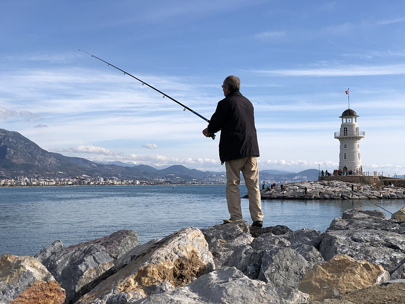 渔夫在灯塔附近钓鱼图片下载