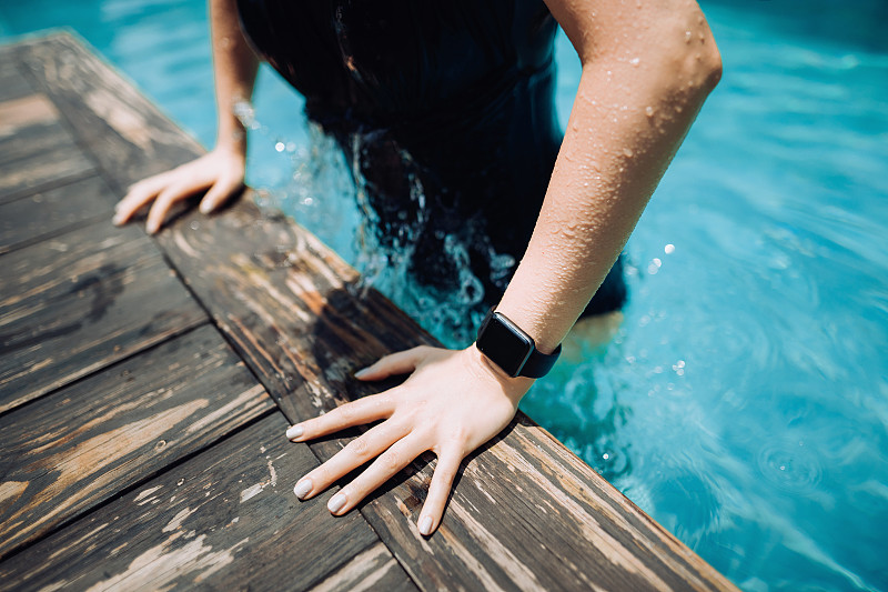 近距离的年轻女性游泳者与智能手表从游泳池出来图片下载