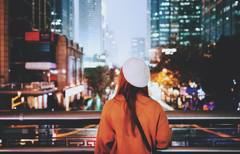 一个年轻女子站在城市的桥上图片下载